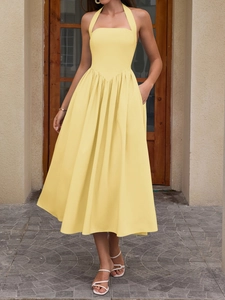 Detail of yellow halter neck dress featuring a V-shaped waist seam and side pockets