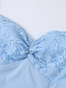 Détail de la robe bleu clair montrant la dentelle florale et le plissage de poitrine