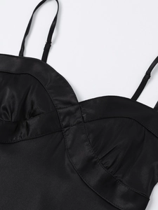 Detail of black satin dress showing adjustable spaghetti straps and pleated bust stitching