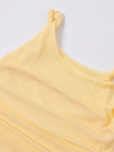 Détail de la robe en maille jaune montrant la texture respirante et la bretelle nouée