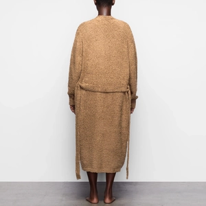 Rear view of a camel plush long cardigan with tie waist belt and soft textured fabric