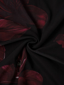 Macro detail of sheer black mesh fabric with dark red floral print and ruched texture