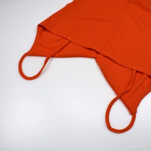 Detail of orange ribbed bodysuit showing spaghetti straps and textured knit fabric