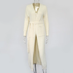 Detail of plush off-white cardigan showing soft texture, belted waist, and deep pockets