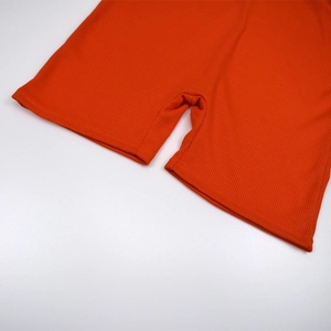 Detailed close-up of orange ribbed knit fabric and neat stitching on slim bodysuit