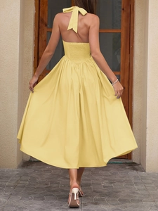 Close-up of the elegant smocked back and oversized halter neck bow on a yellow midi dress