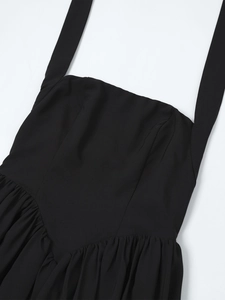 Detail of black halter neck dress with square neckline and ruched pleated fabric texture