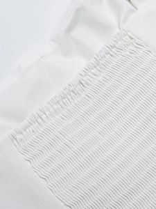 Detailaufnahme der weißen gesmokten Stoffstruktur an einem Sommerkleid