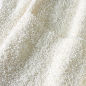 Macro view of plush white fleece fabric texture showing soft curly fibers for winter robes