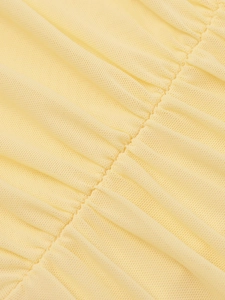 Détail macro du tissu en maille jaune clair montrant les coutures froncées sur la robe
