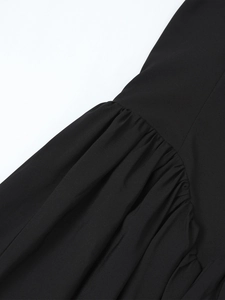 Detailed view of black ruched fabric texture and pleated craftsmanship on backless dress