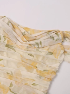 Detailed view of yellow floral mesh fabric with elegant ruched textures on the dress