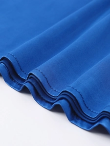 Detailed close-up of the royal blue satin dress hem with smooth stitching and silky texture