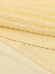 Détail du tissu en maille jaune clair montrant les coutures surjetées professionnelles