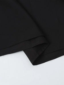 Detailed macro view of the double-stitched hem on the black halter neck dress fabric