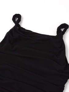 Détail de robe en maille noire avec tissu froncé et une bandoulière torsadée