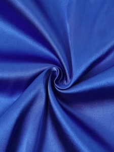 Close-up detail of smooth royal blue satin fabric with elegant silk texture and spiral folds