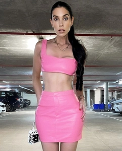 Detail of pink PU leather two-piece set featuring a cropped vest and mini skirt on model