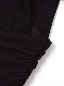 Détail du tissu en maille noire montrant la texture froncée et le tricot alvéolé ajouré