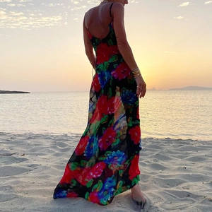 Detailed back view of a sexy backless floral maxi dress with vibrant print on a beach at sunset