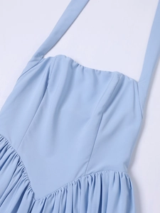 Detail of light blue halter dress featuring a ruffled hem and pleated waist details