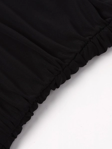 Détail du tissu en maille noire avec des fronces élastiques sur une robe moulante