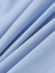 Macro shot showing light blue woven fabric texture with detailed fine stitching