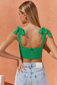 Detail of emerald green crop top with bow straps and visible silver back zipper