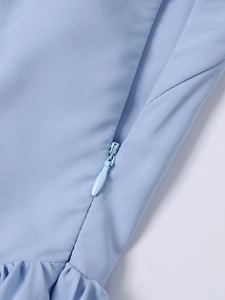 Detail view of the concealed teardrop zipper and ruffled texture on light blue dress fabric