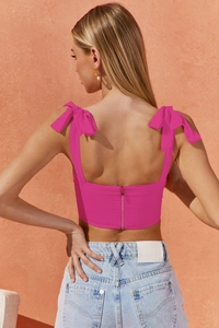 Detail showing the back of a pink bow strap crop top with metallic zipper and blue jeans