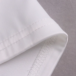 Détail macro de l'ourlet à double surpiqûre et texture satinée sur une robe blanche