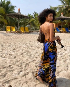 Detail of a backless maxi dress with abstract blue and orange print on a sunny beach