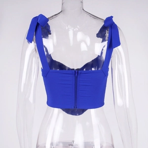 Rear view of bright blue corset top featuring oversized shoulder bows and hidden zipper