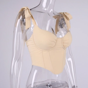 Detail of beige corset top featuring ribbon bow straps and structured boning seams