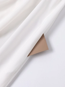 Detailed close-up of white textile fabric texture with elegant draping and brown card detail