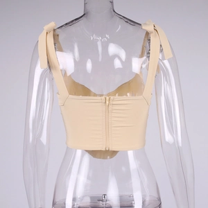 Detail view of apricot cropped top featuring back zipper and decorative shoulder bows