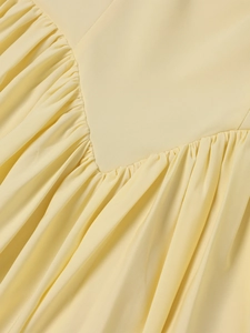 Close-up of light yellow dress fabric featuring unique V-shaped seams and gathered pleats