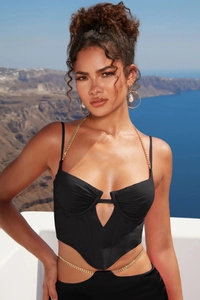 Dettaglio del corsetto nero con catene dorate e design con intaglio a rombo