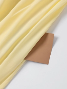 Detail of light yellow satin dress showing silky texture and soft glossy fabric finish