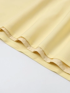 Close-up of light yellow woven fabric showing clean inner hem stitching and soft texture