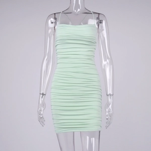 Detail of mint green ruched bodycon dress with crisscross straps on a mannequin