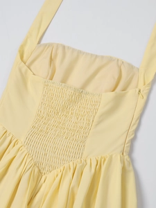 Detail of smocked elastic back and invisible zipper on light yellow halter dress