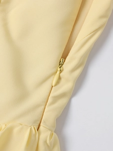 Detail of hidden zipper and fine pleats on the pale yellow halter midi dress