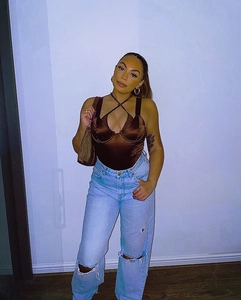 Brown satin criss-cross halter bodysuit paired with high-waist ripped blue jeans