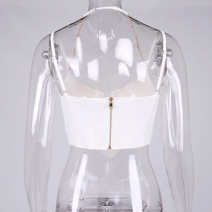 Dettaglio della cerniera dorata e della catena sul retro del top a corsetto bianco
