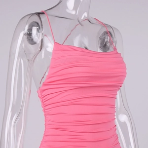 Detailed close-up of neon pink ruched fabric and thin straps on a bodycon dress