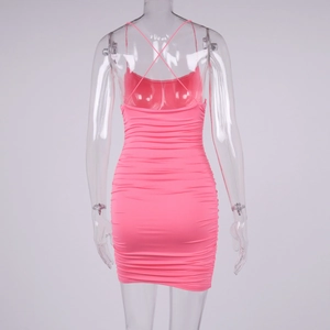 Detail of pink bodycon dress featuring backless cross straps and ruched textured fabric
