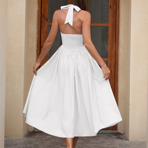 Elegant backless white halter midi dress with a tied bow and smocked waist detailing