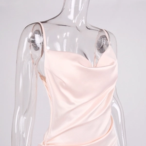 Detail of light pink satin slip dress featuring a cowl neck and silk texture