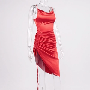 Macro detail of red satin dress featuring cowl neck and side drawstring ruched texture